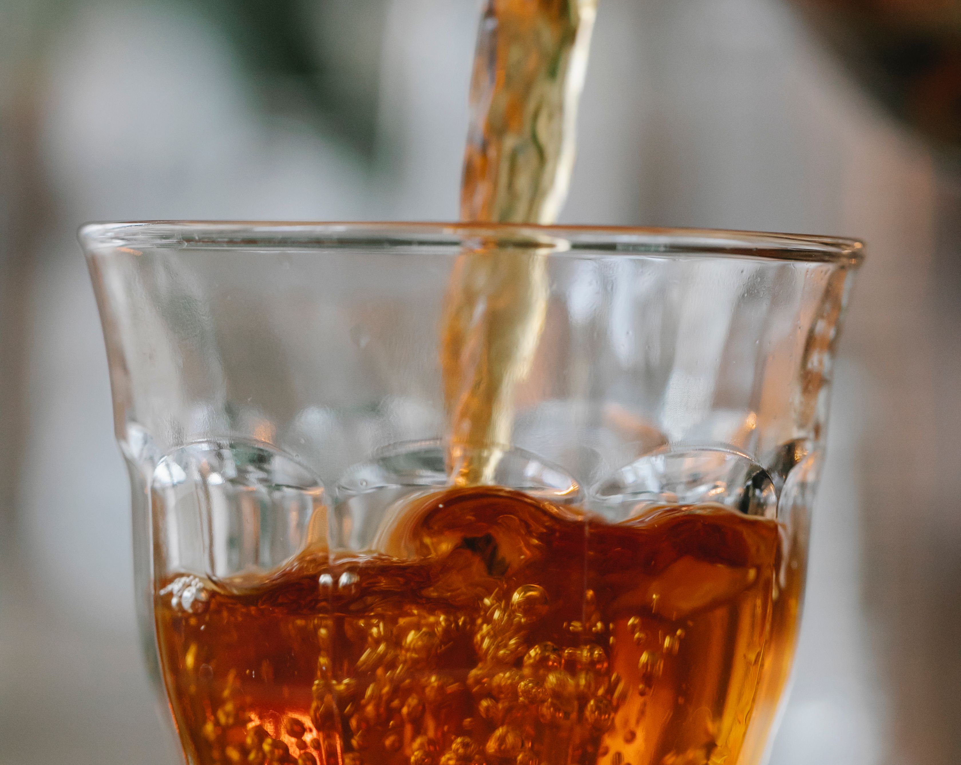 Freshly brewed black tea being poured into a clear glass cup