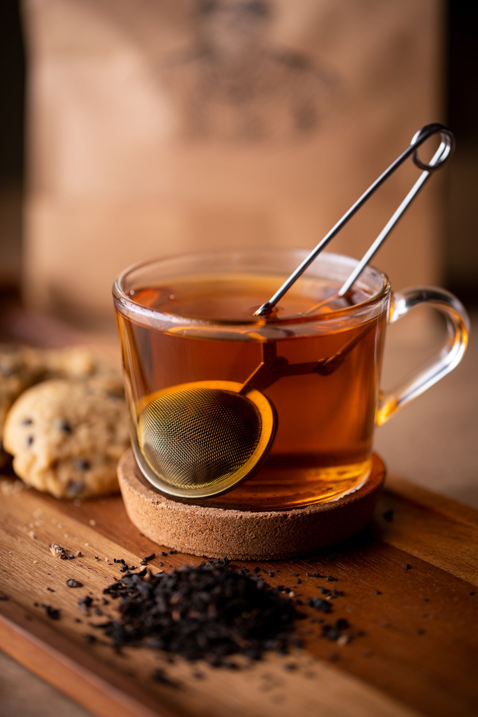Loose-leaf tea steeping in a glass infuser beside a cup